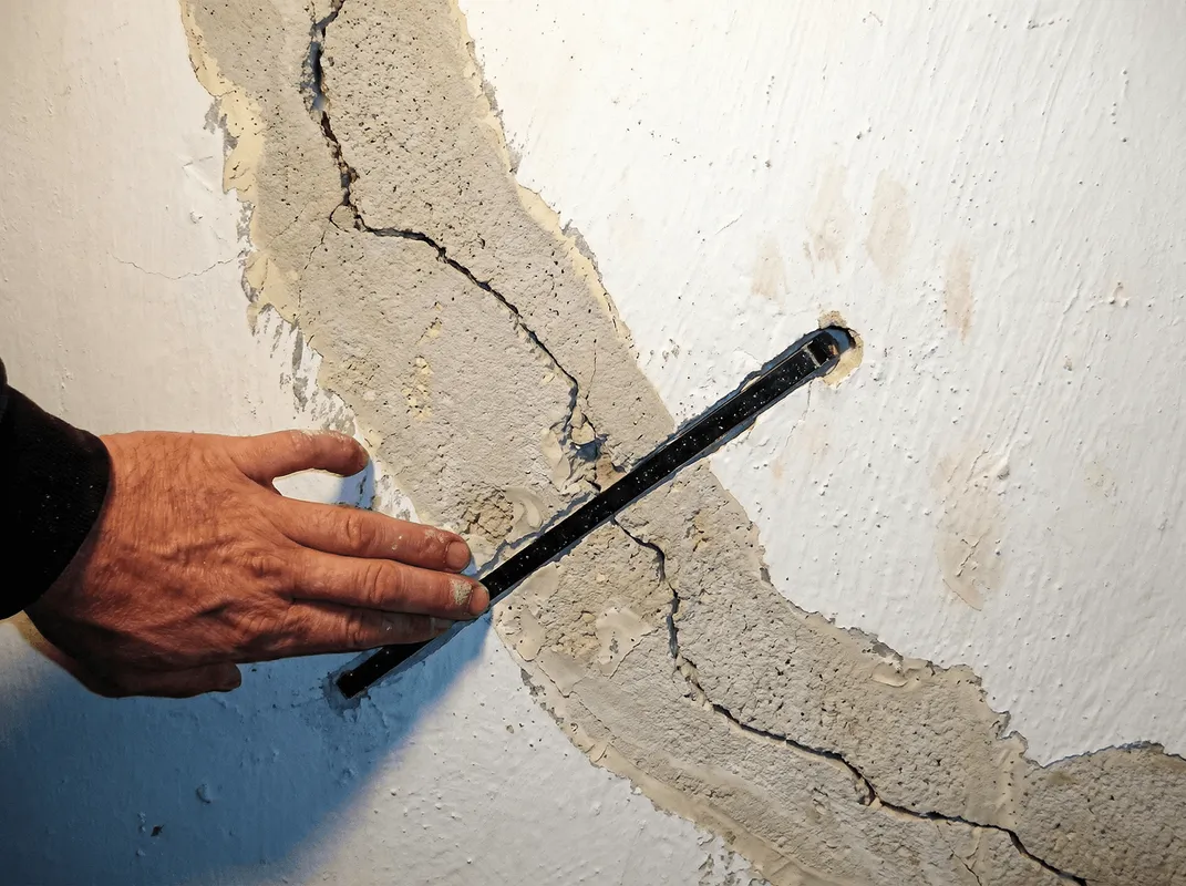 A wall with a large crack is being inspected by a professional in Fargo, ND
